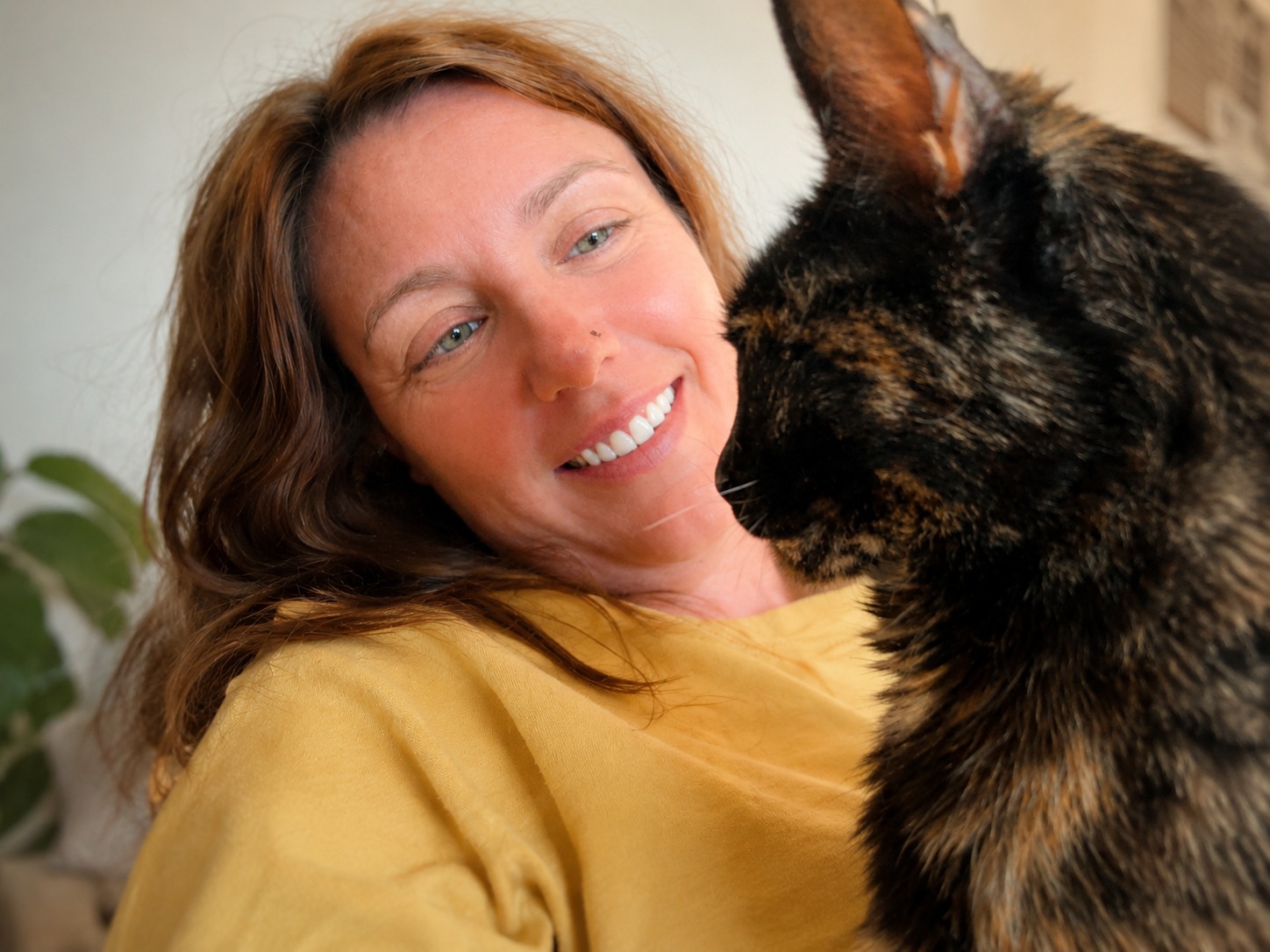 Ana Anglada sonriendo mientras su gata se acerca a su cara